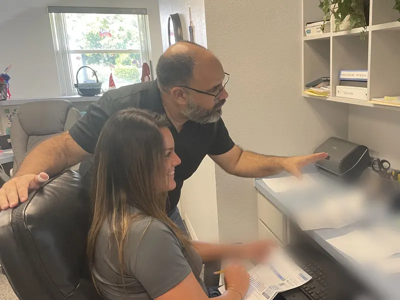 Javier at a client's desk, walking her through something on screen