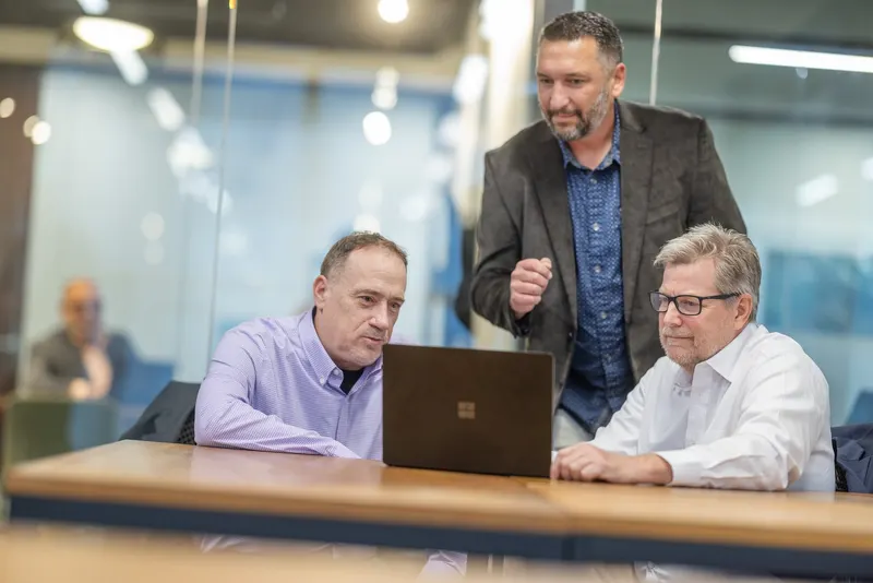 Three of the team at one laptop